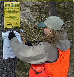 woman posting conservation sign on tree